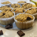 banana chocolate chunk muffins with oatmeal on a white plate with chocolate chunks on plate.
